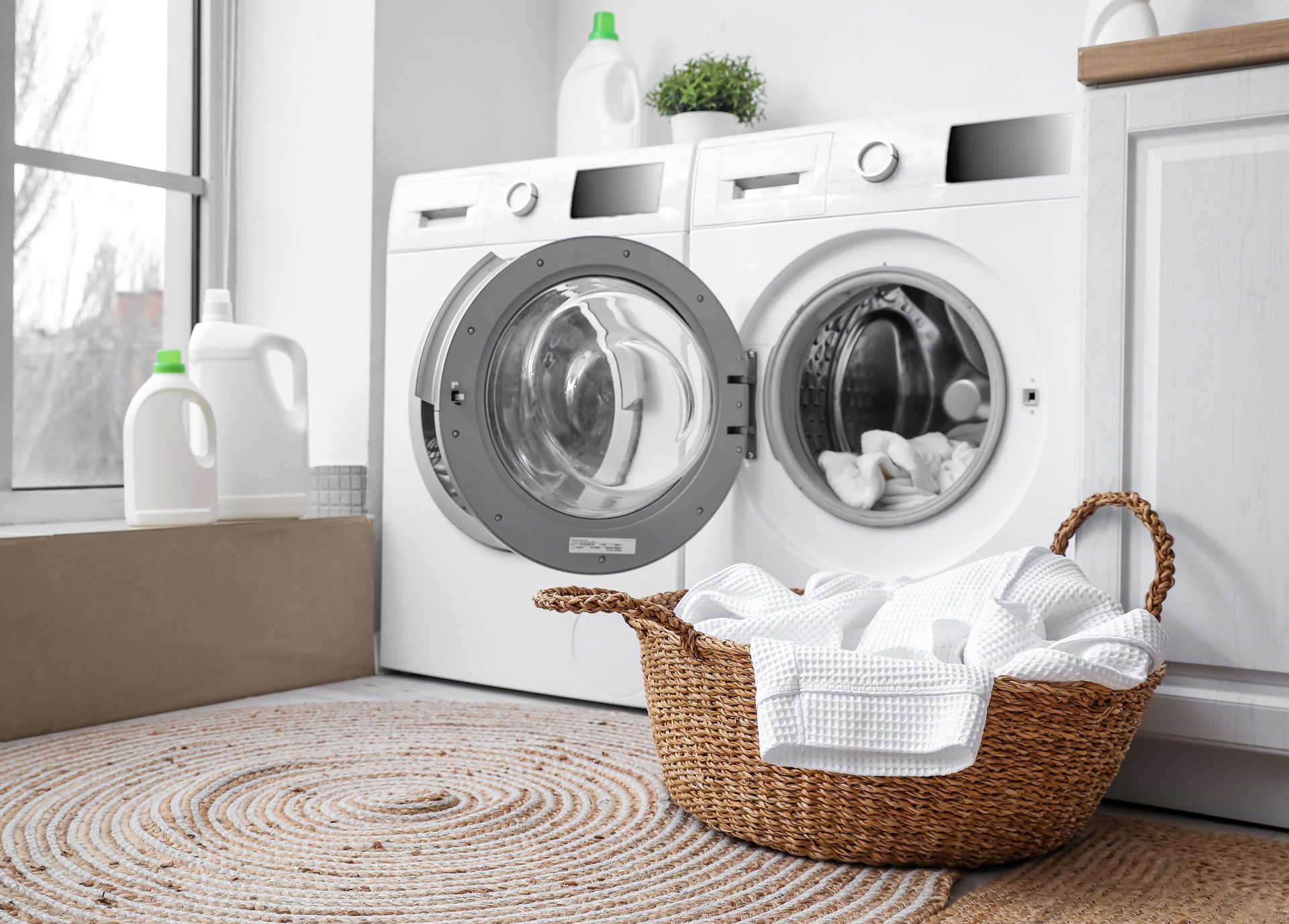 A laundry room with a washer and dryer and a basket of clothes.