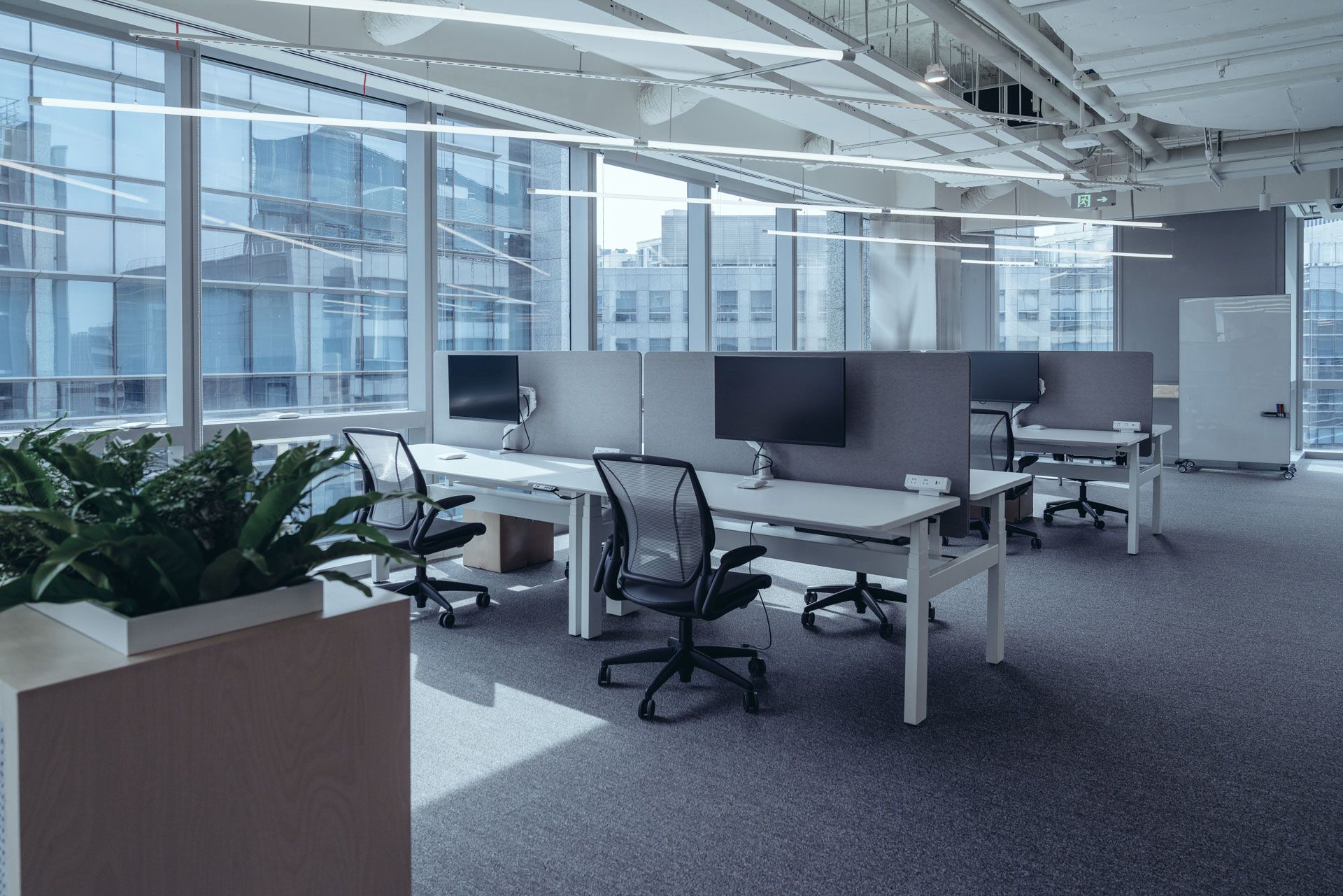 A large empty office with a lot of windows and desks and chairs.
