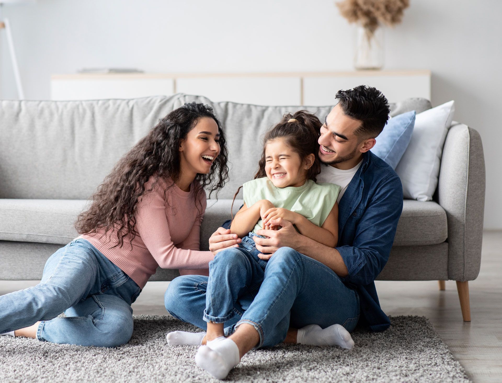 A family is sitting on the floor in front of a couch.