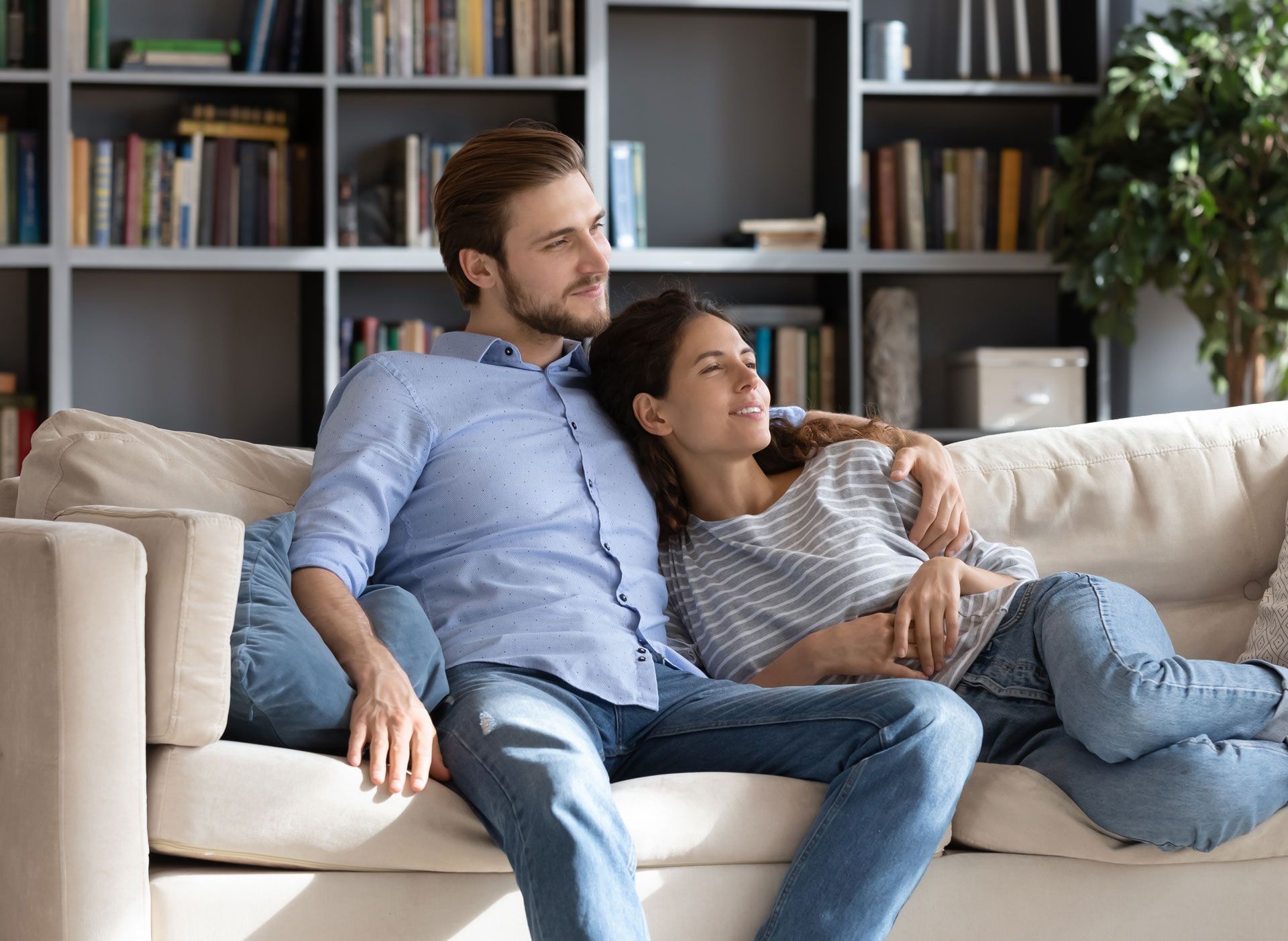 A man and a woman are sitting on a couch in a living room.