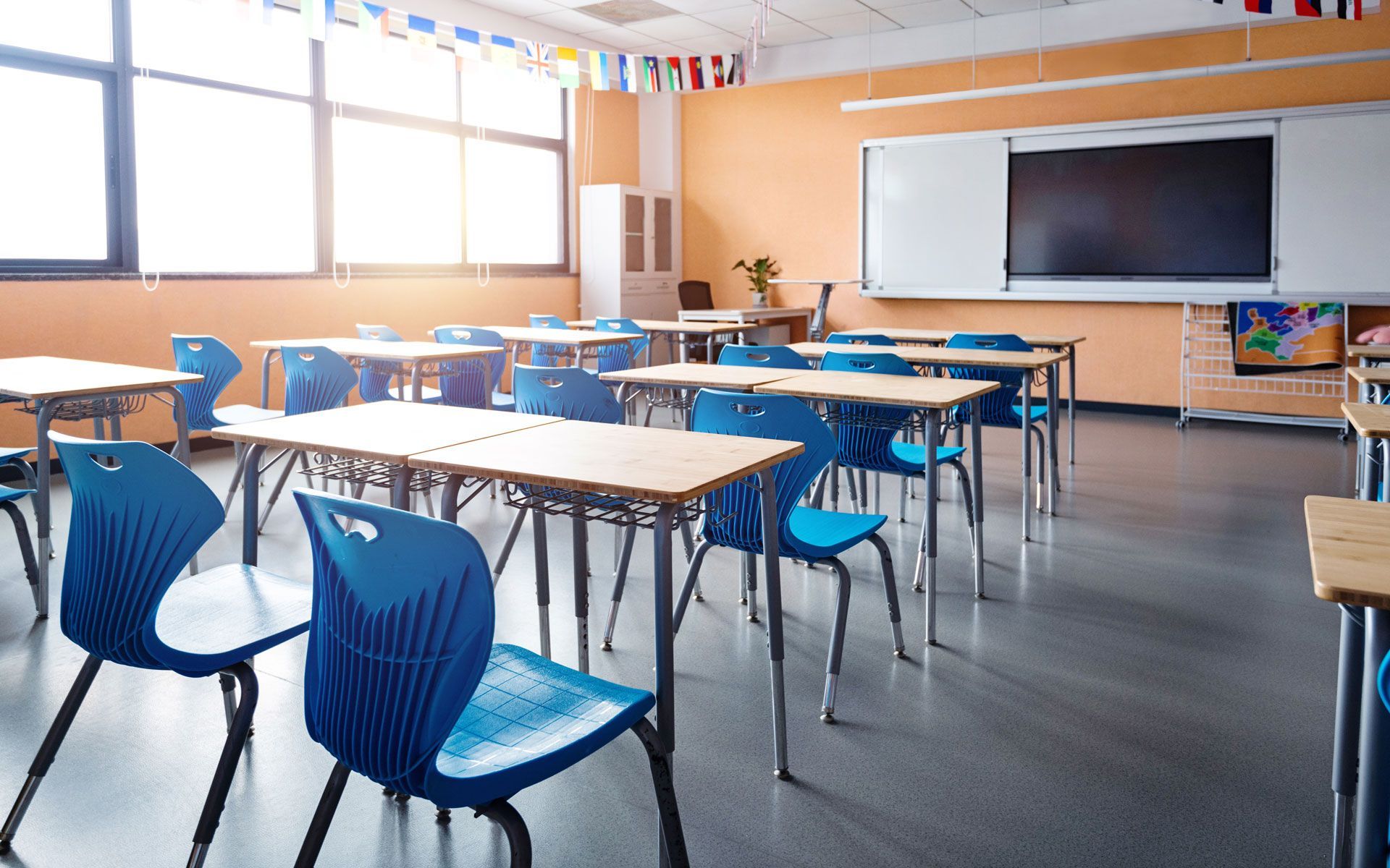 An empty classroom with blue chairs and tables.