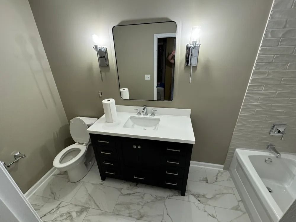 A bathroom with a toilet , sink , mirror and bathtub.