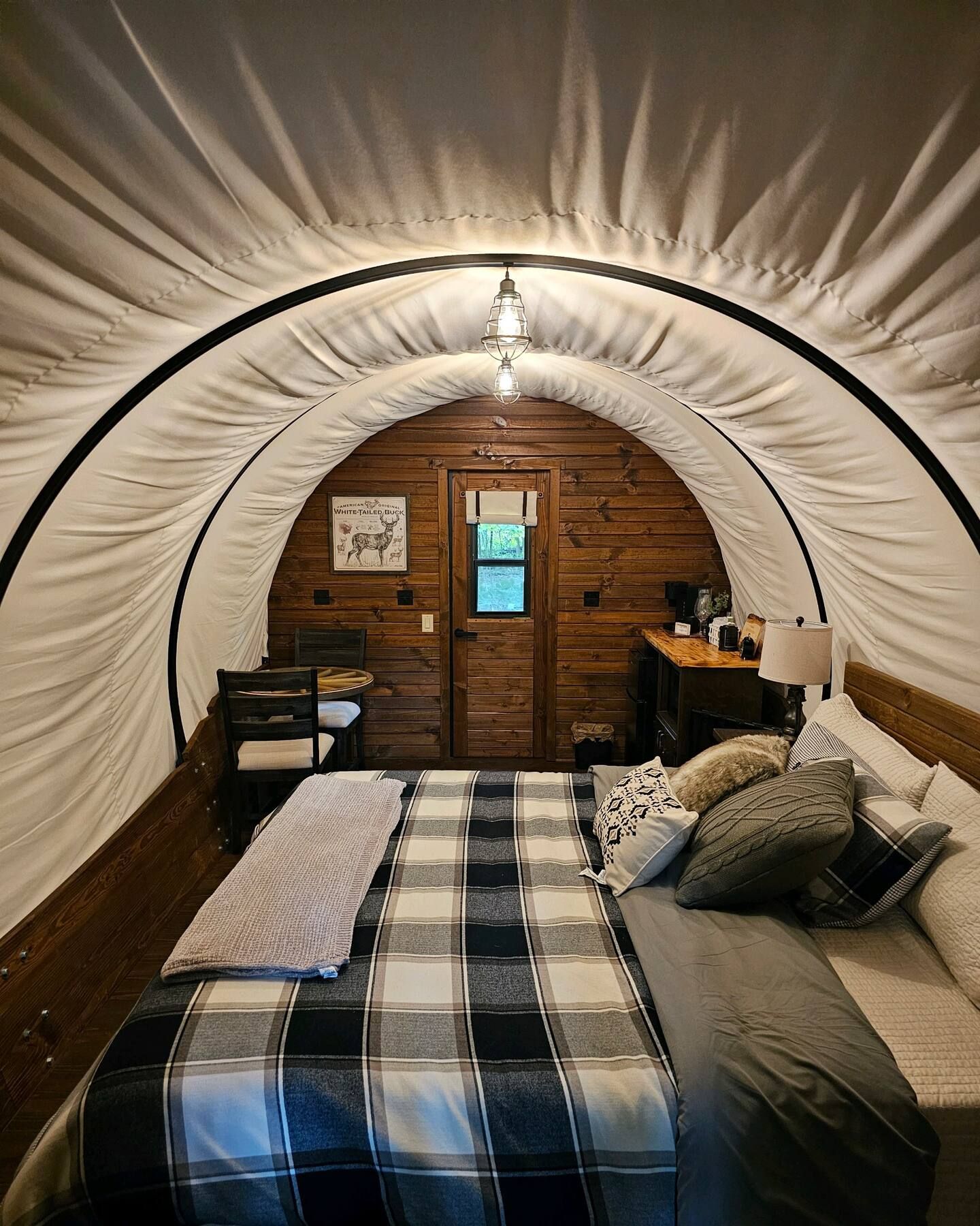 A bed is sitting inside of a covered wagon.