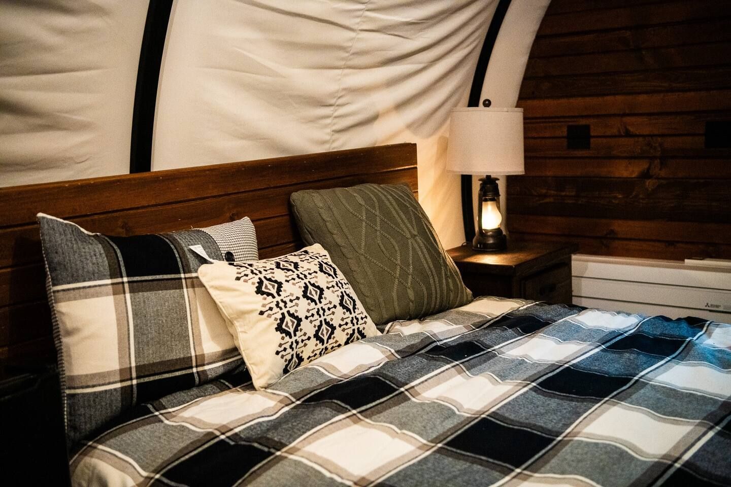 A bed with a plaid comforter and pillows in a cabin.