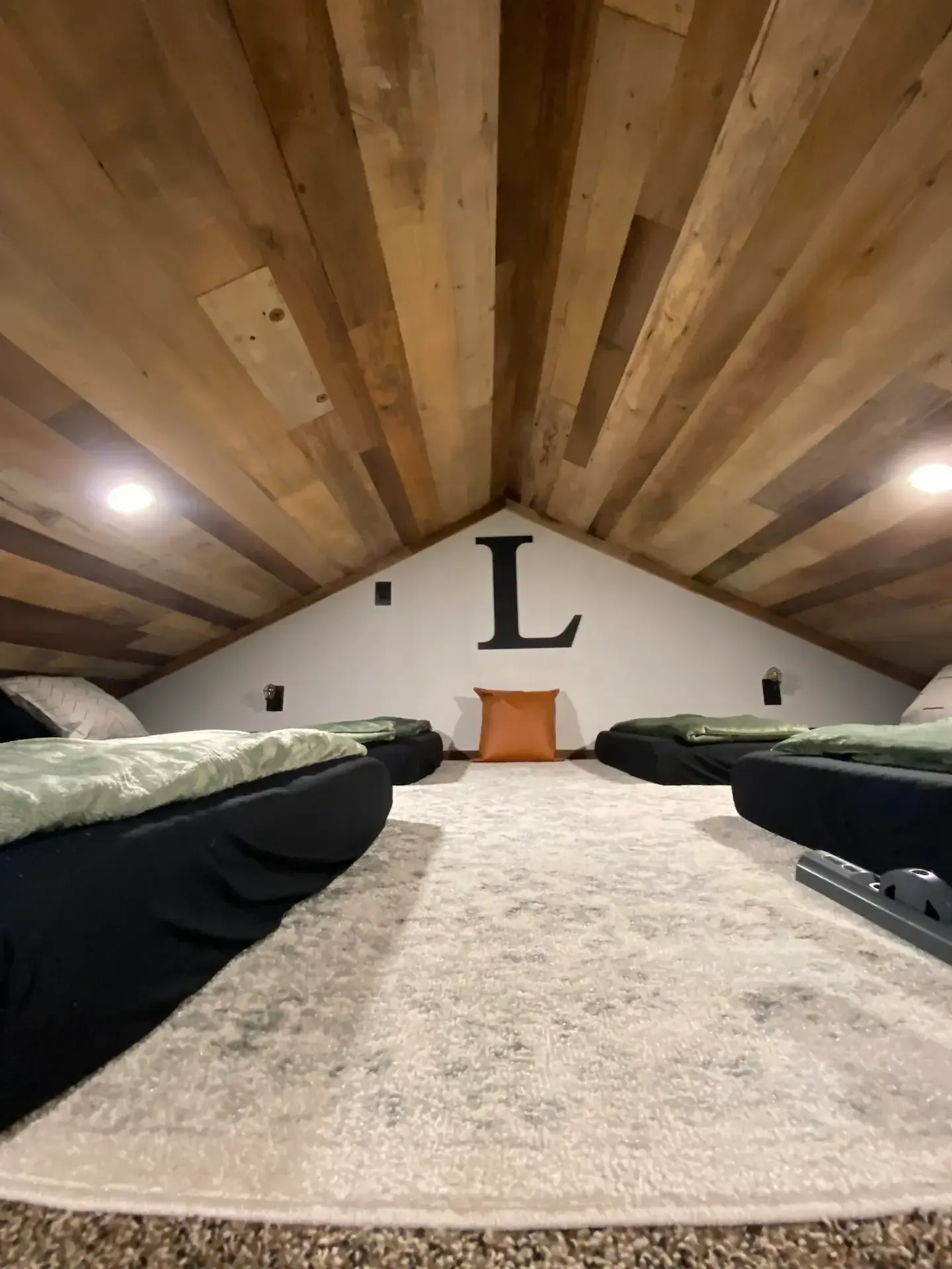 There are two beds in the attic with a letter l on the wall.