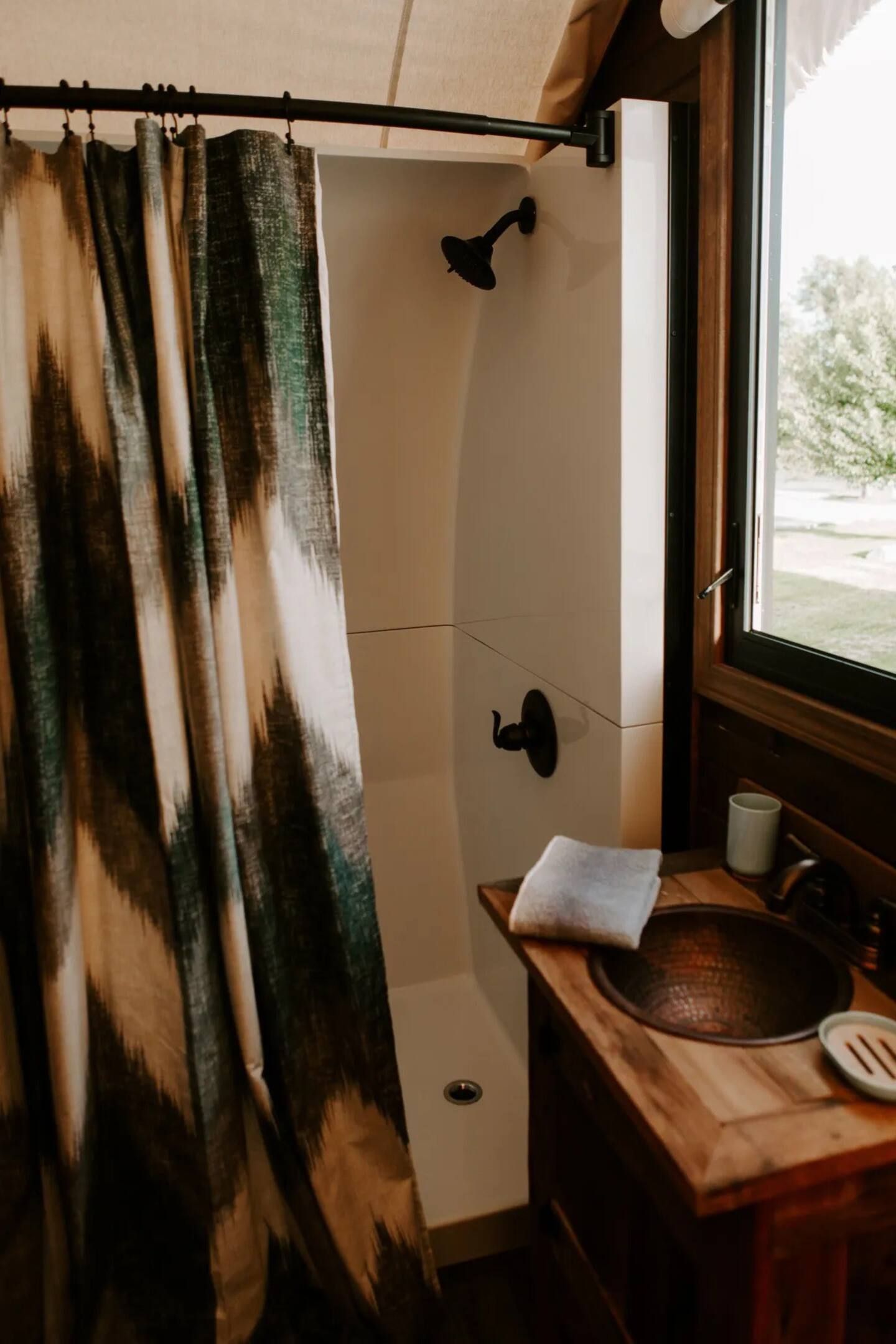 A bathroom with a sink , shower , and window.
