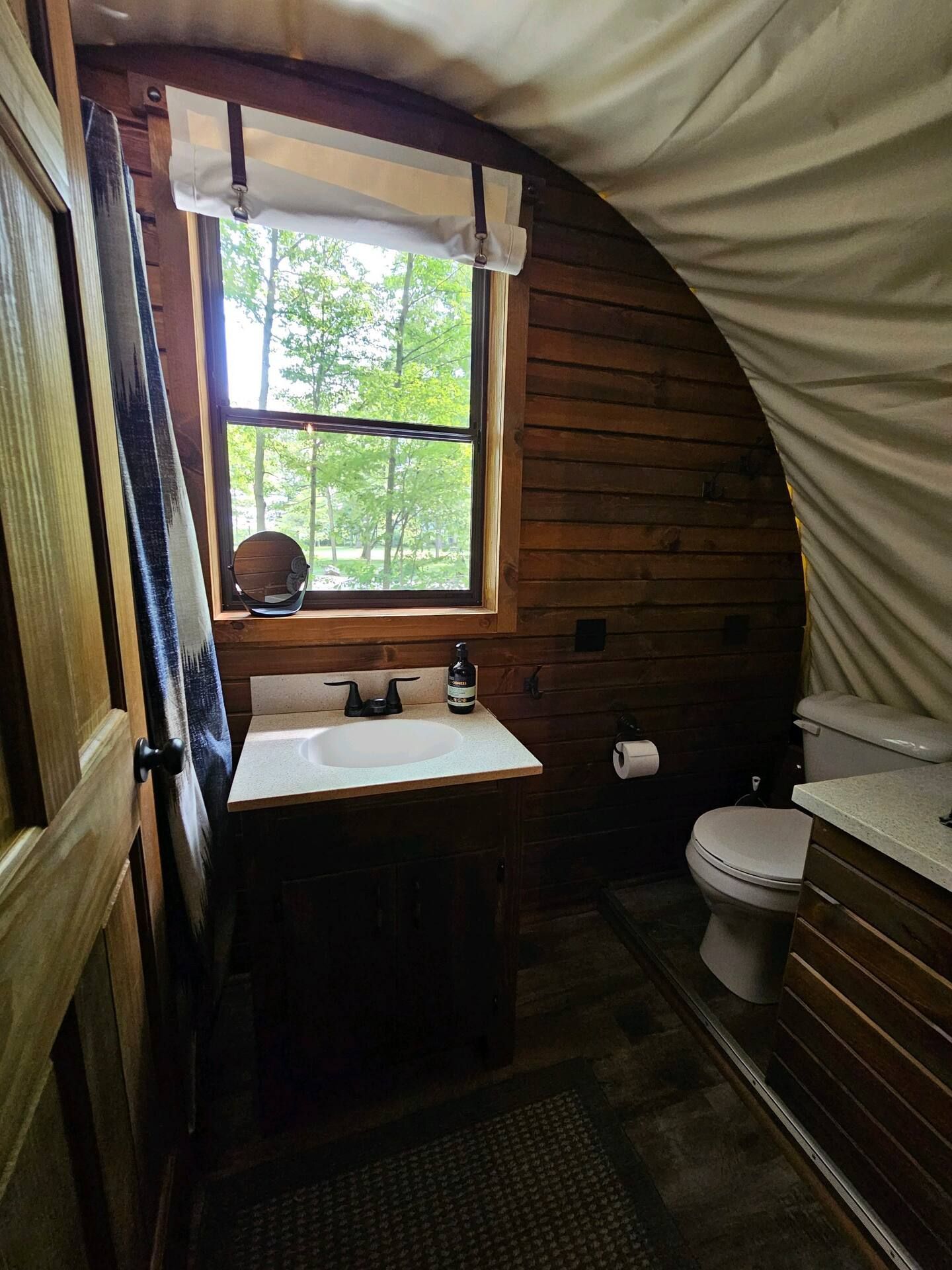 A bathroom with a sink , toilet and window.