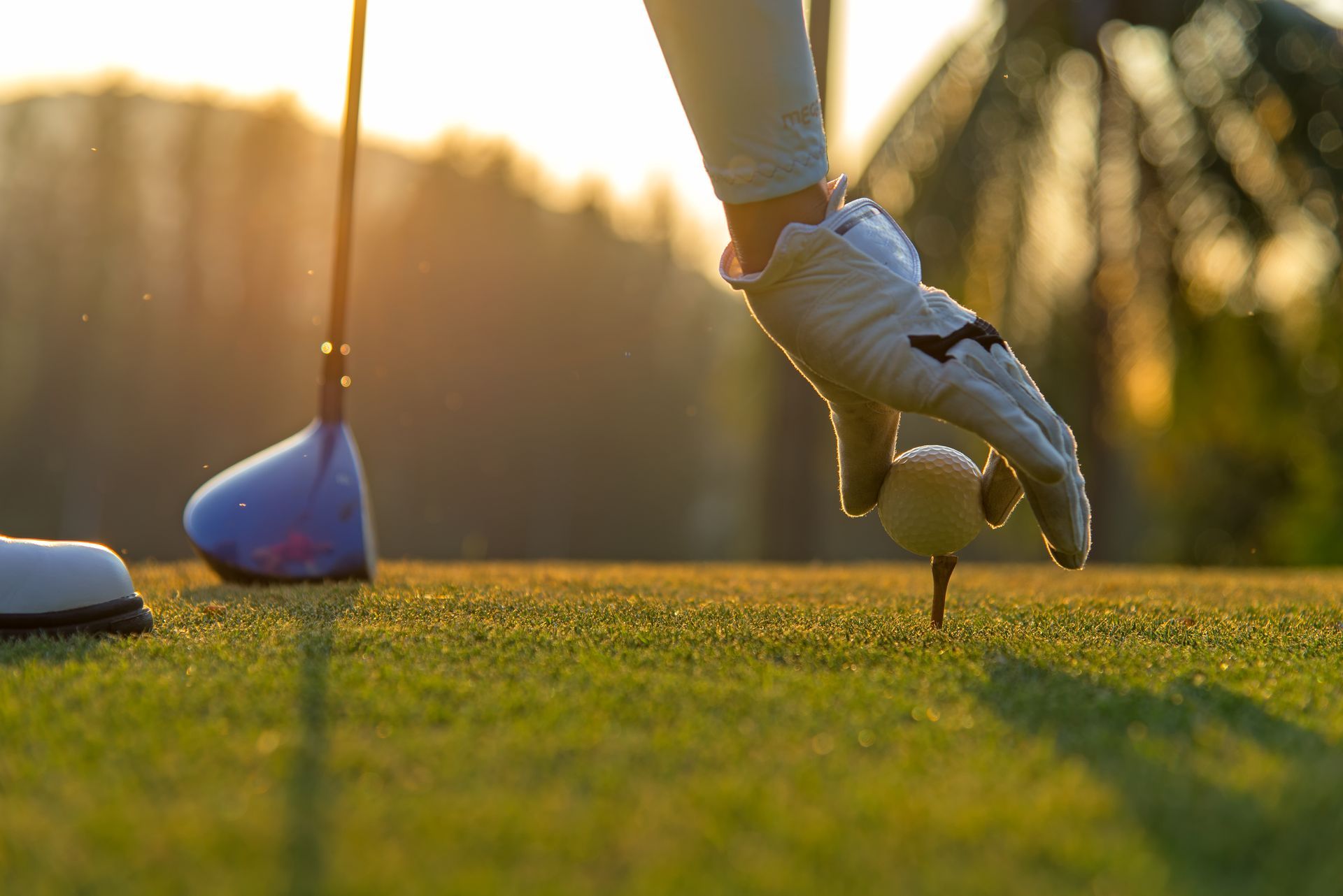 A person is putting a golf ball on a tee on a golf course.