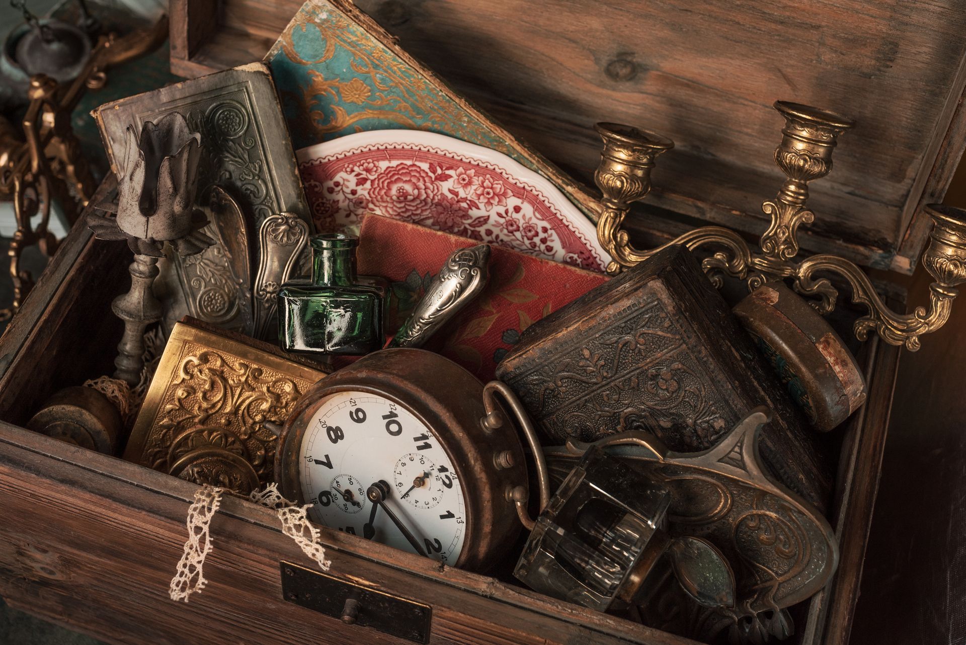 A wooden chest filled with lots of antique items and a clock.