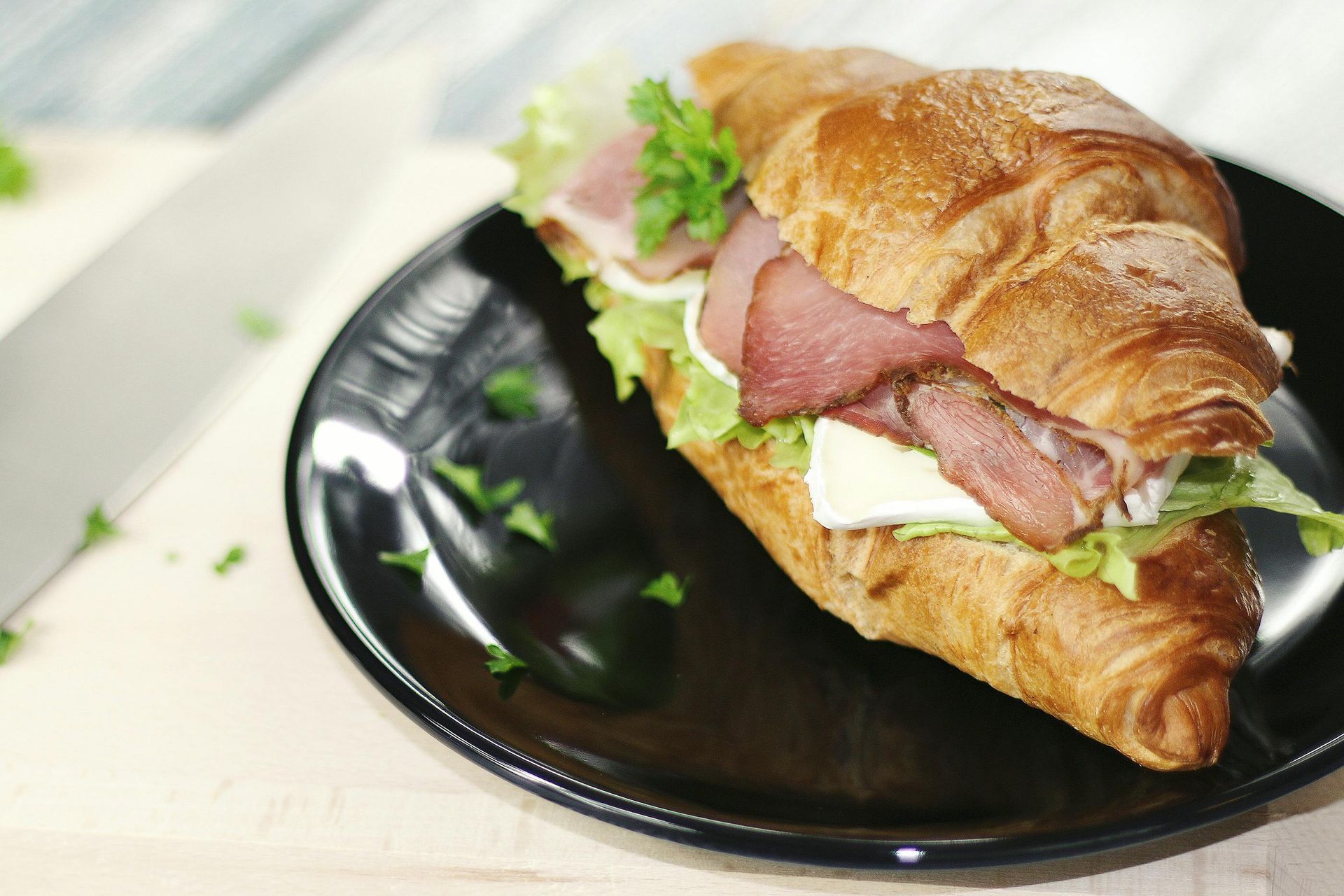 A sandwich on a croissant on a black plate