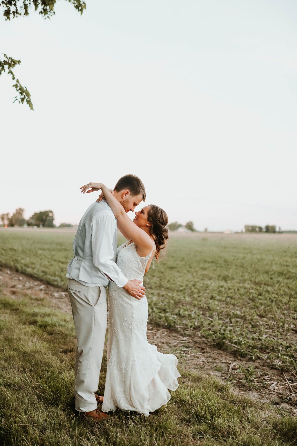 A bride and groom are kissing in a field.