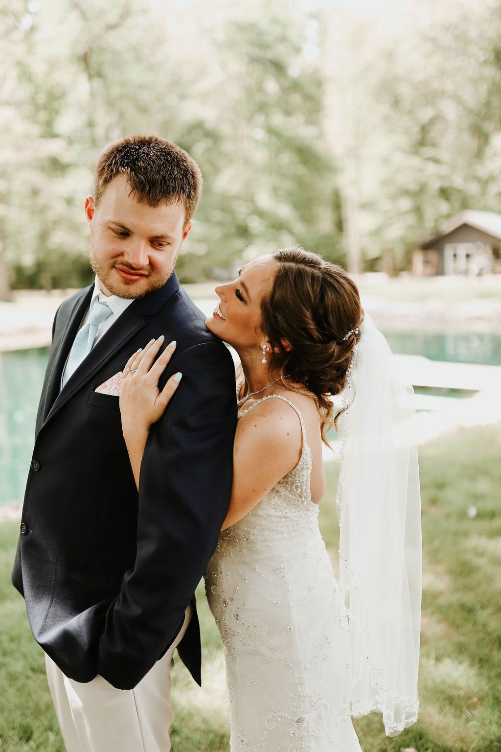 A bride and groom are posing for a picture in front of a pool.