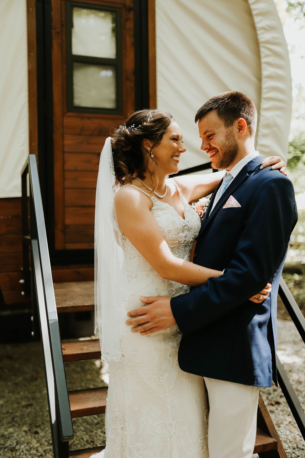 A bride and groom are posing for a picture in front of a wagon.