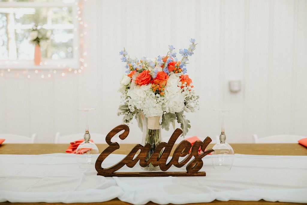 A wooden sign is sitting on a table next to a vase of flowers.
