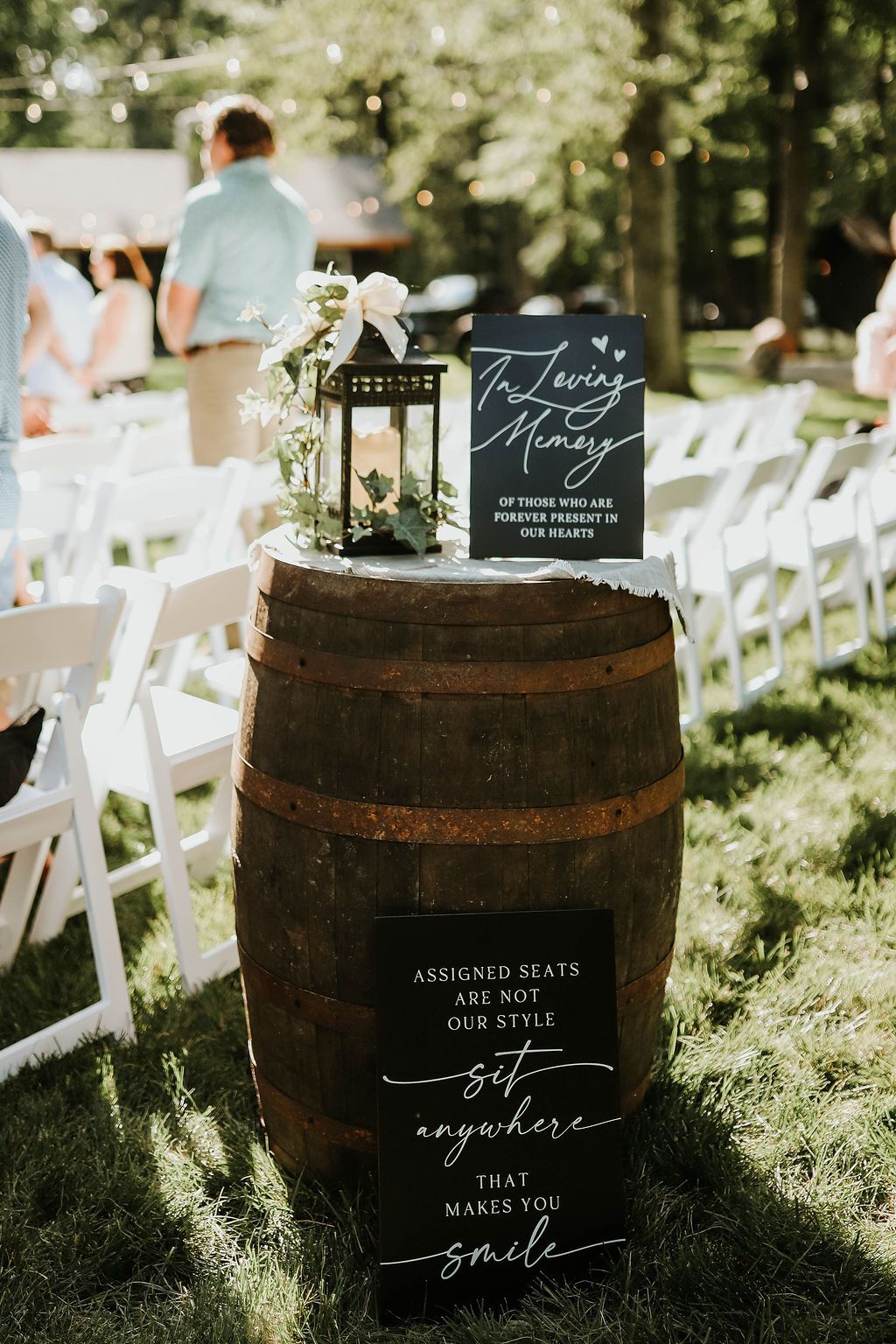 A wooden barrel with a sign on top of it is sitting in the grass.