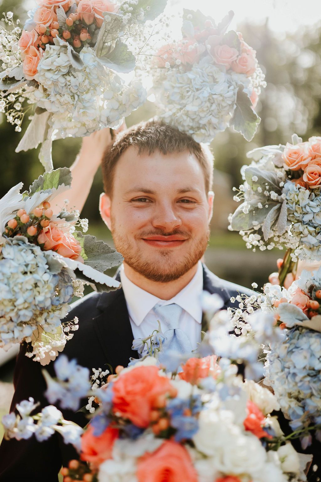 A man in a suit and tie is surrounded by flowers.