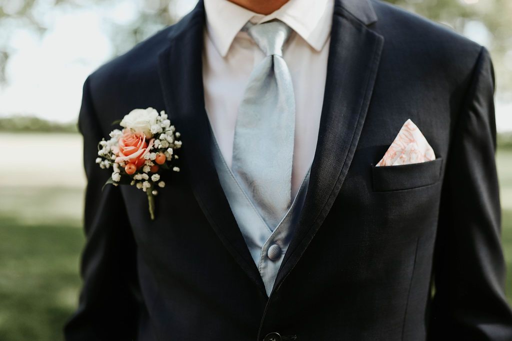 A man in a suit and tie with a flower in his pocket.