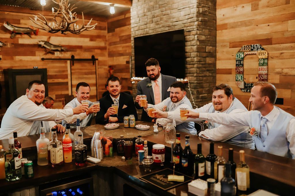 A group of men are sitting at a bar toasting with beer.