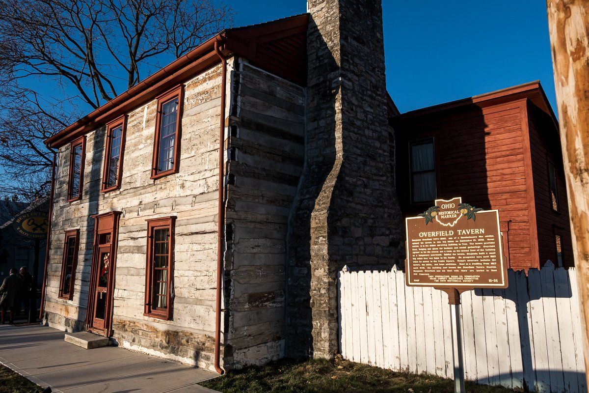 A wooden house with a sign in front of it.