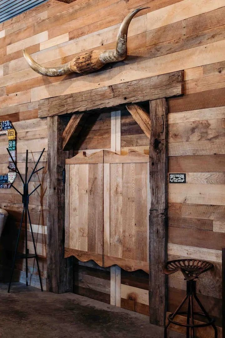 A wooden door with a skull on the wall above it.