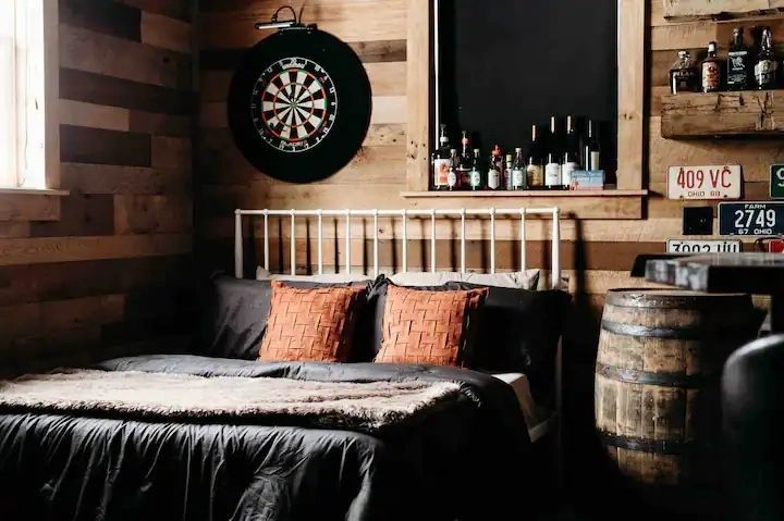 A bedroom with a bed and a dart board on the wall.