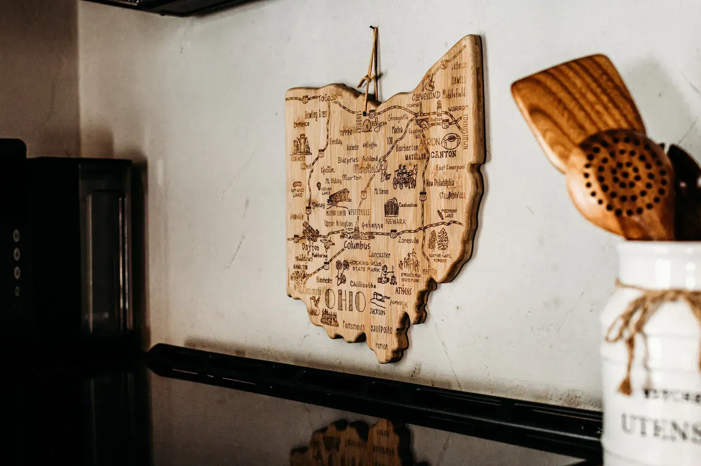 A wooden map of ohio is hanging on a wall in a kitchen.
