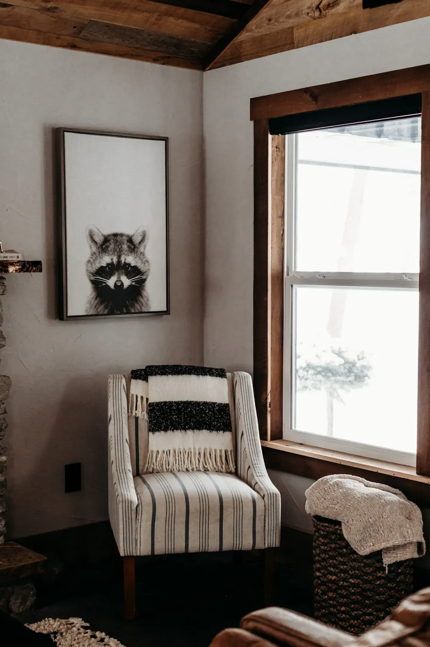 A living room with a chair and a picture of a raccoon on the wall.