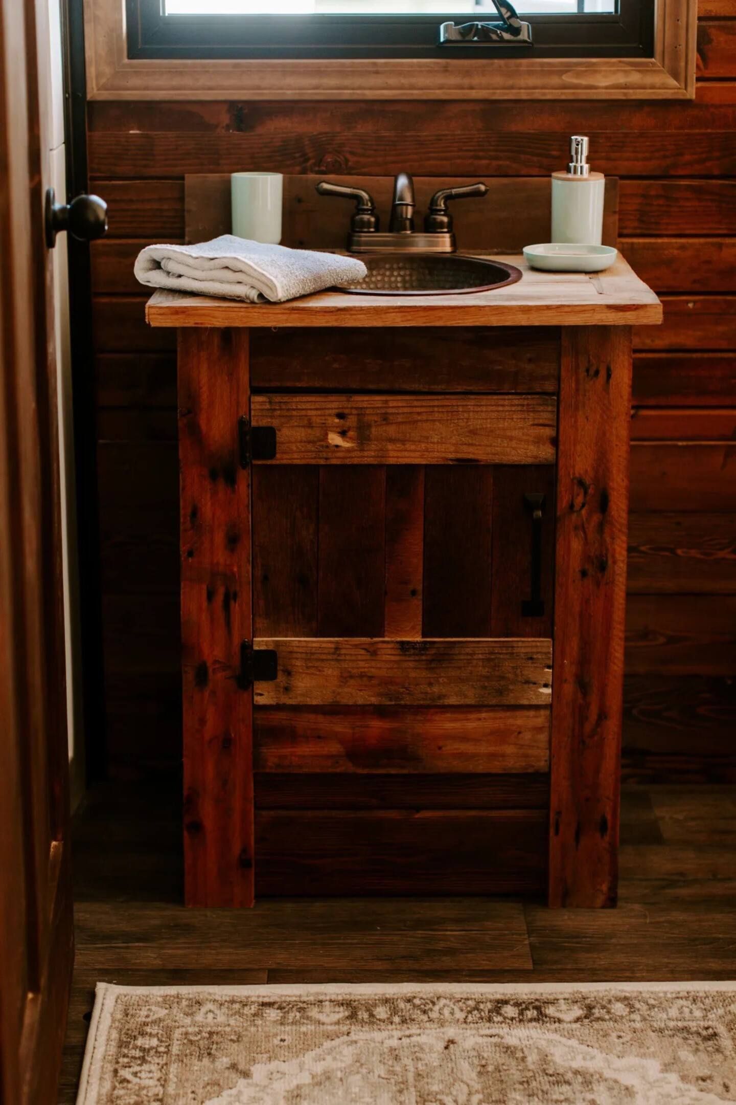 A bathroom with a wooden sink and a window.
