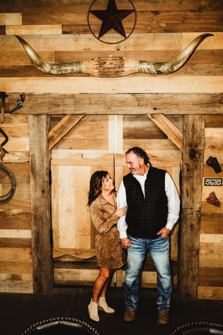 A couple standing and chatting in a rustic wooden room with a star and wagon wheel decor.