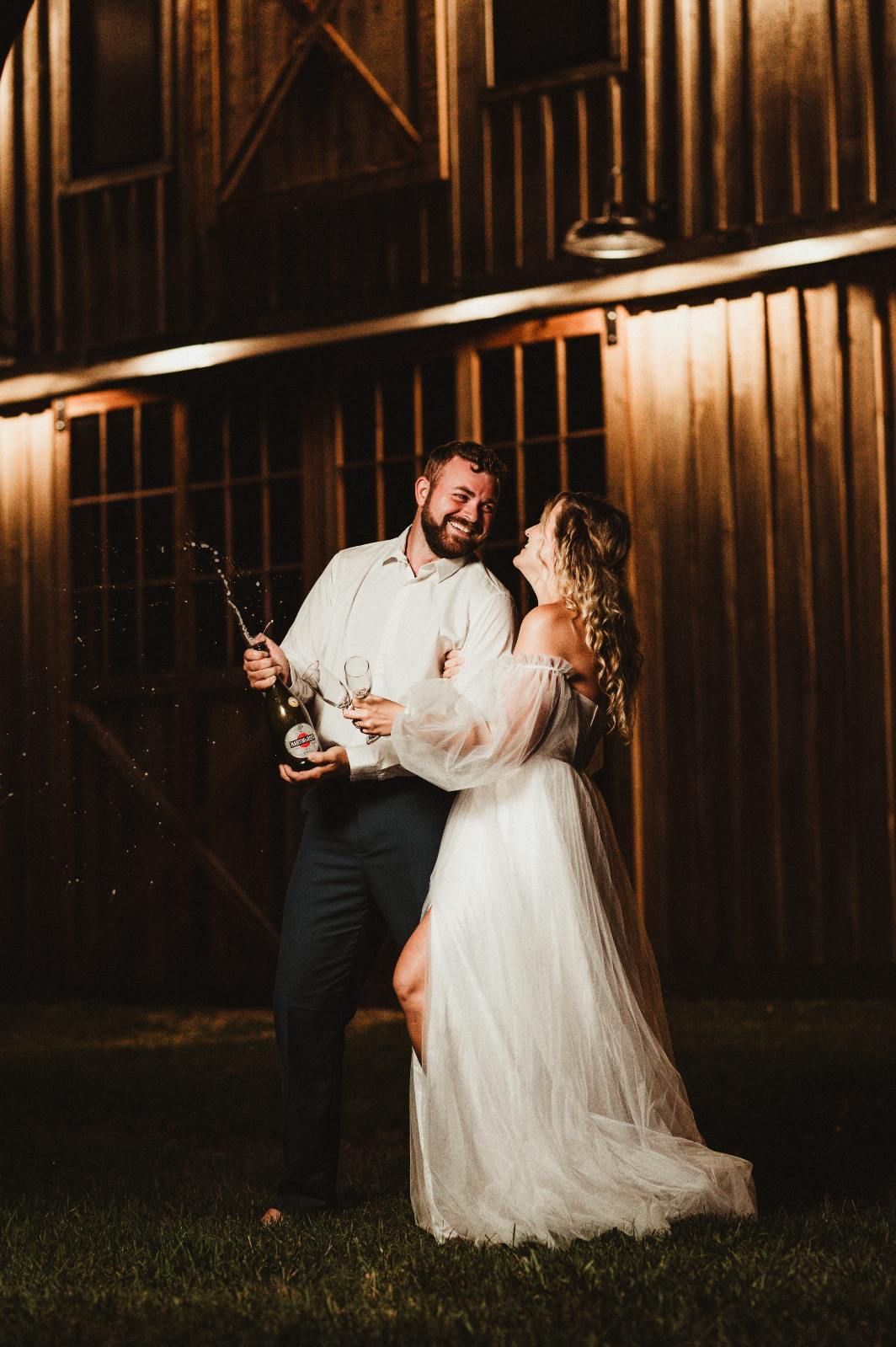 Couple dancing with sparklers in front of a wooden barn at night