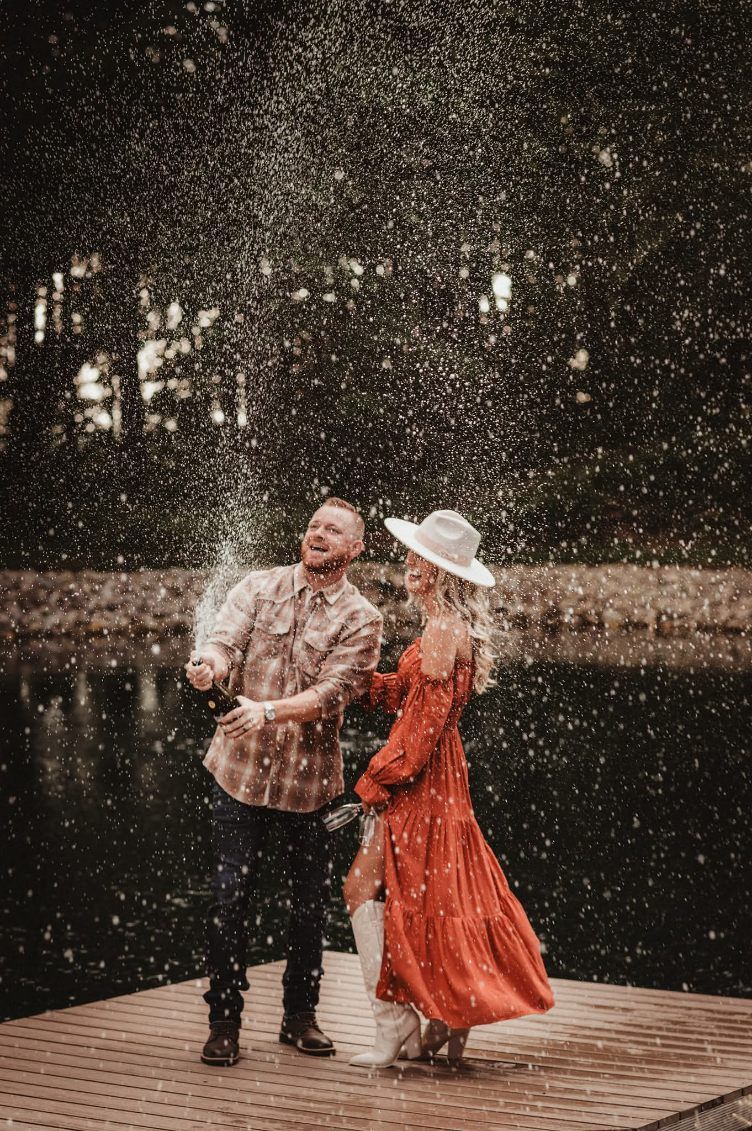 Couple dancing on a wooden platform in falling snow, with the woman in an orange dress and white hat.