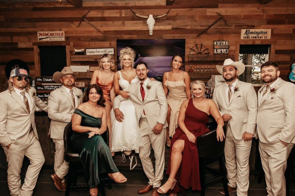 Group of formally dressed people posing in a rustic wooden room, like a wedding party.