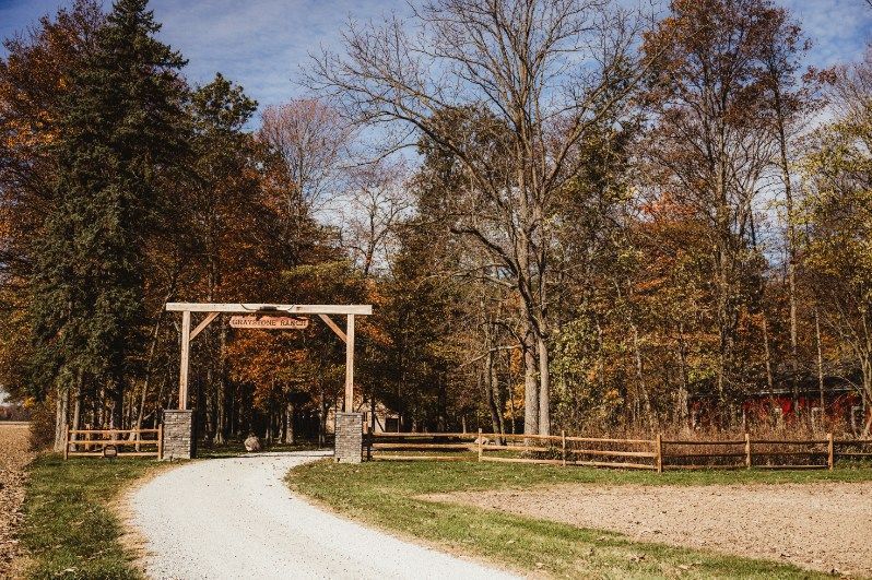Gravel path leading through a wooden gate into a tree-lined park in autumn.