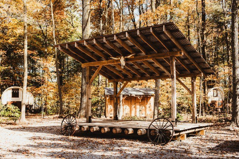 Rustic wooden stage in an autumn forest with wagon wheels and fallen leaves