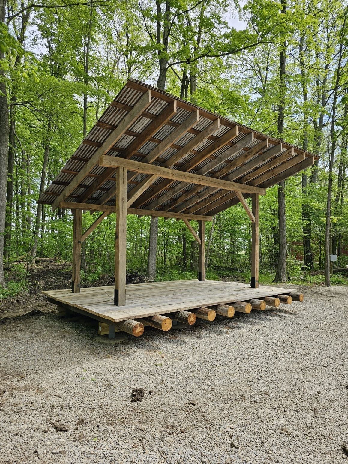 A wooden structure with a roof in the middle of a forest.