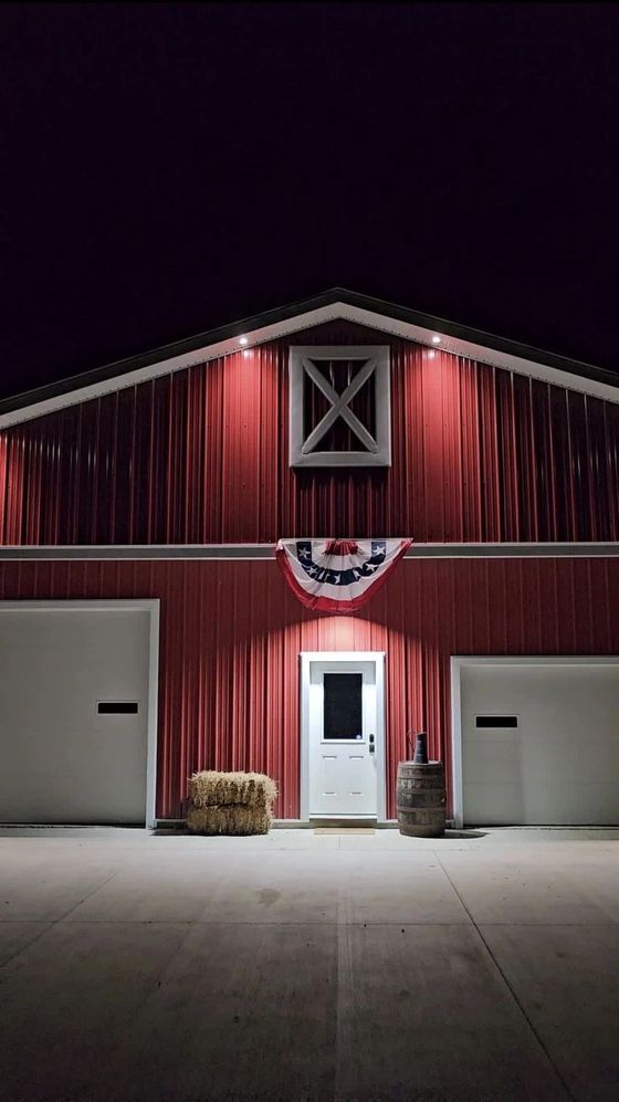 A red barn with a white door is lit up at night.