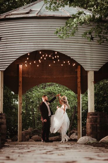 A bride and groom are dancing under a gazebo.