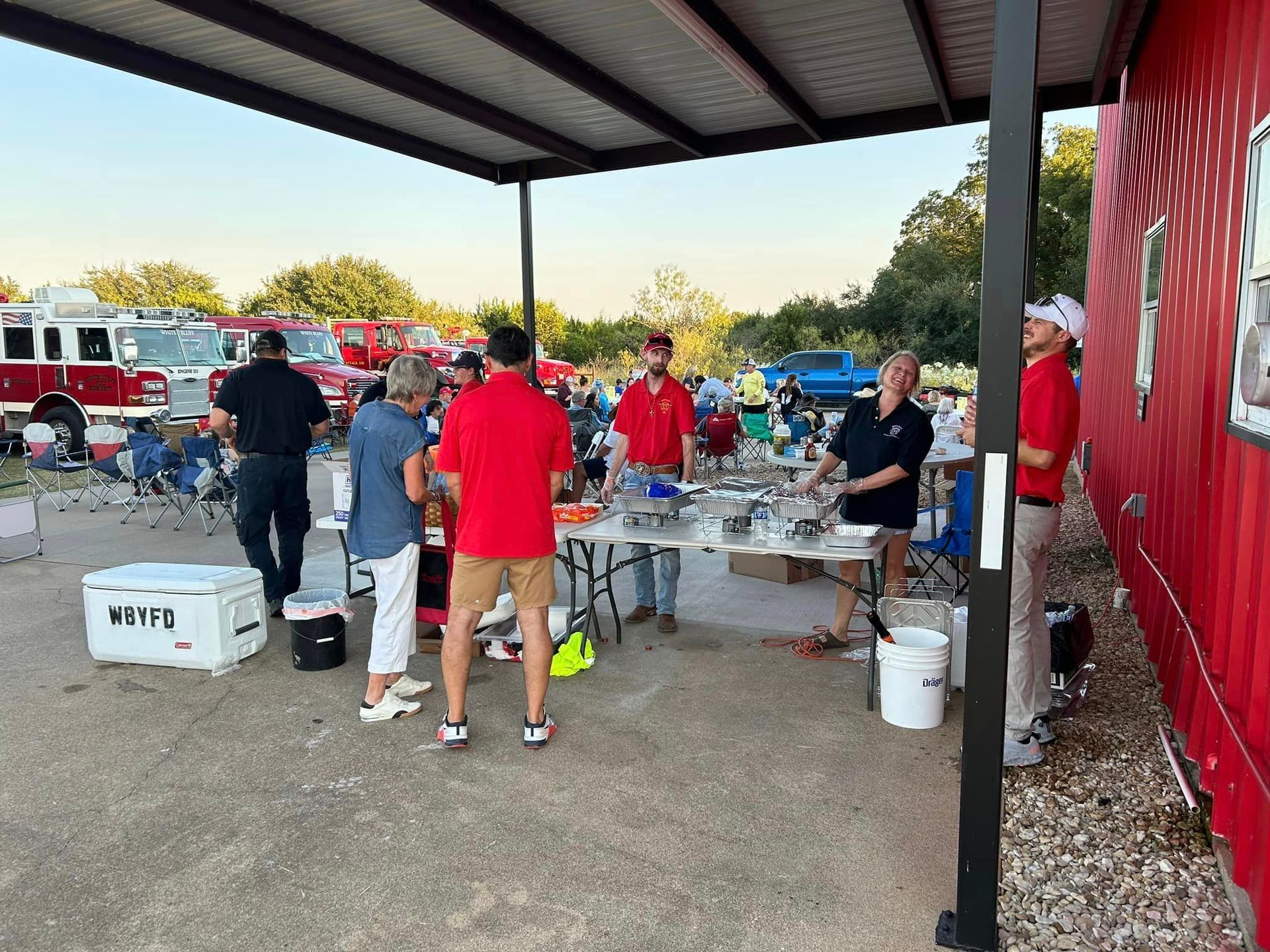 A group of people are standing around tables under a canopy.
