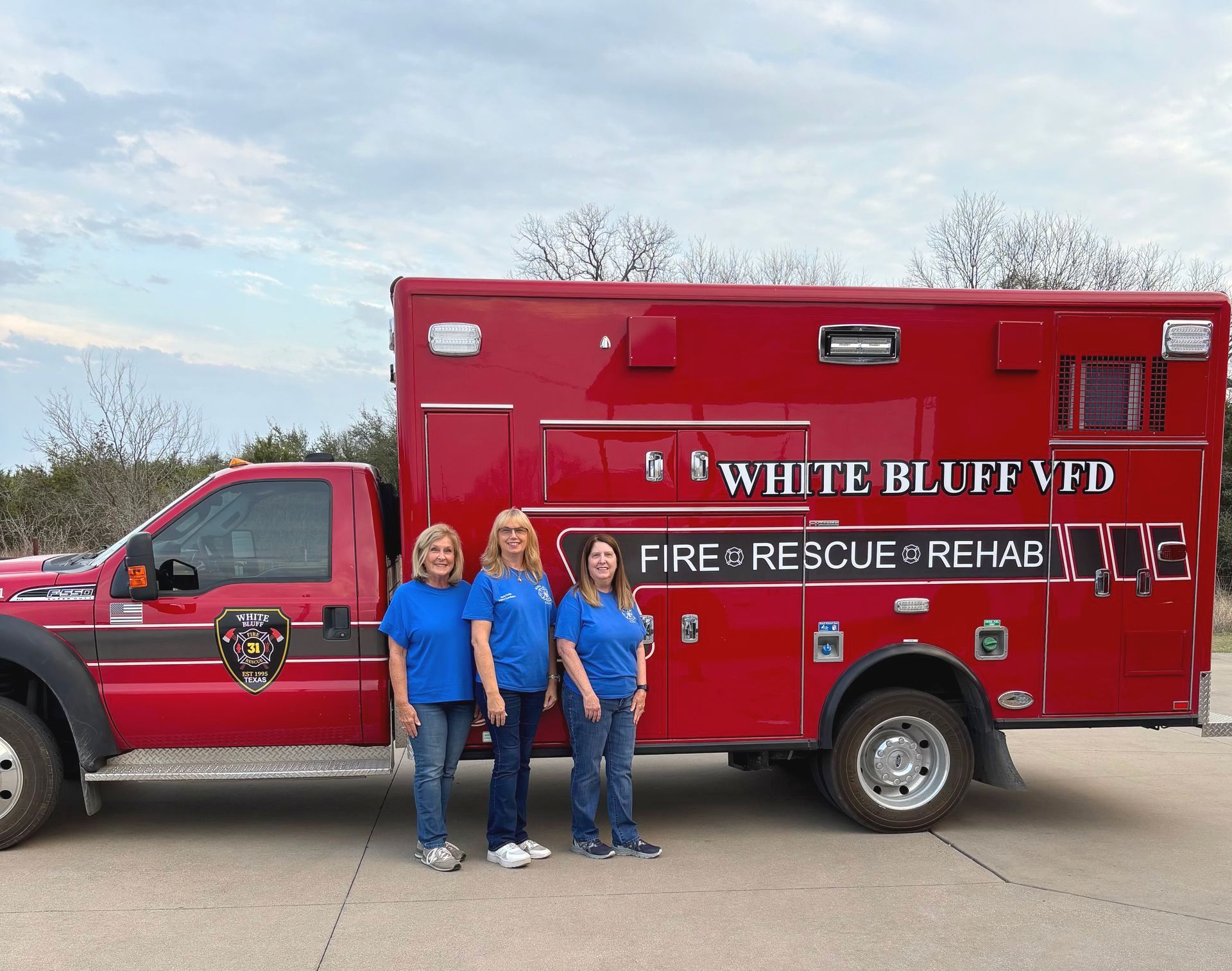 Three women standing in front of a Fire Rescure Red Truck