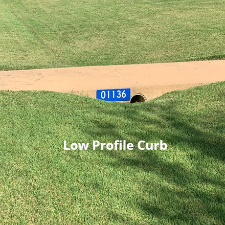 A blue sign on the side of a road says `` low profile curb ''.