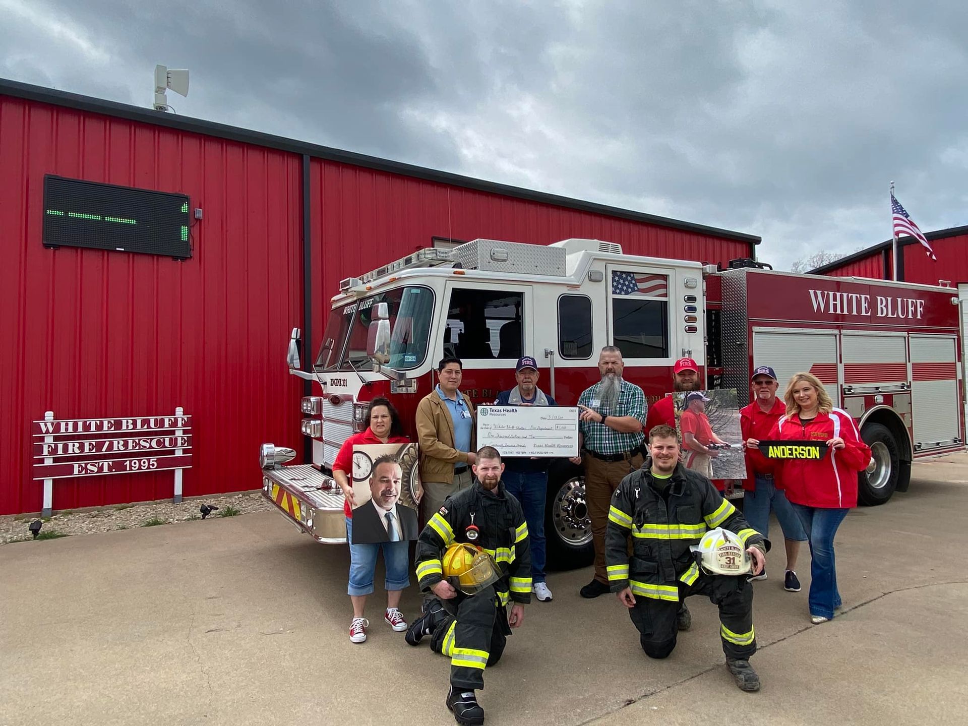 A group of firefighters are posing for a picture in front of a fire truck.