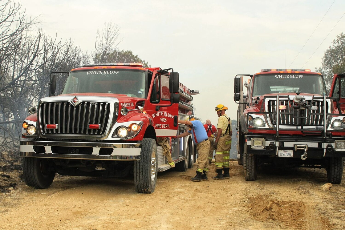 Two fire trucks are parked next to each other on a dirt road.