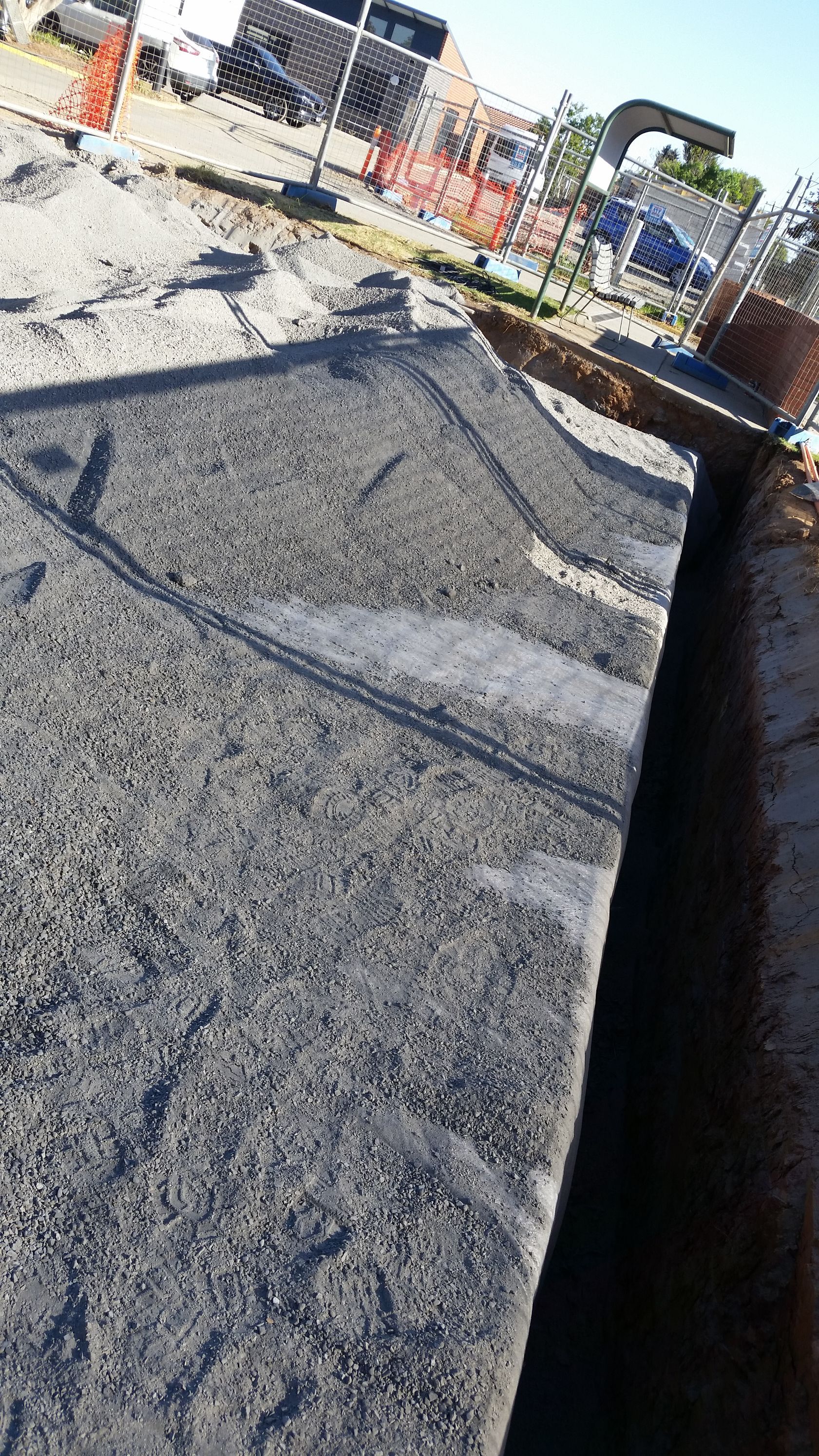 A man is working on a large green pipe in the dirt.