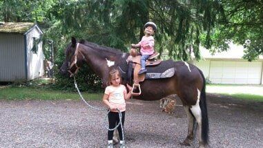 Young girl leading another young girl on horse - Horse riding lessons in Olalla WA