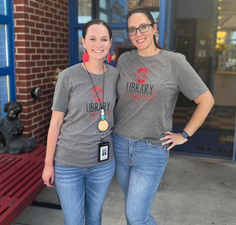 Two women wearing library shirts stand next to each other