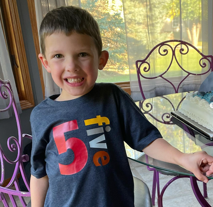 A young boy wearing a shirt with the number 5 on it
