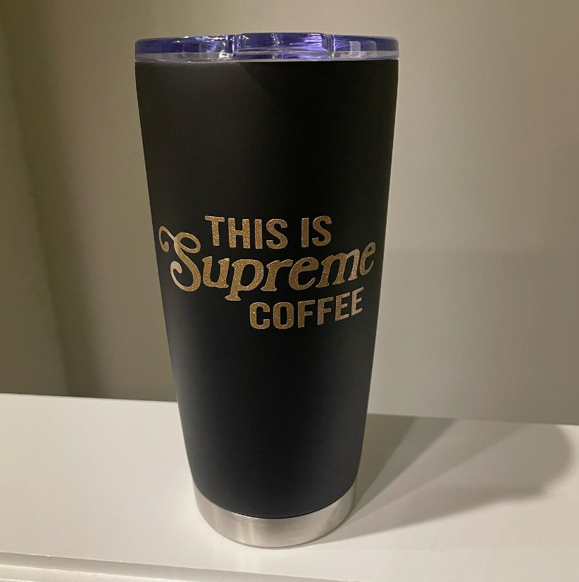 A black tumbler with the words `` this is supreme coffee '' on it