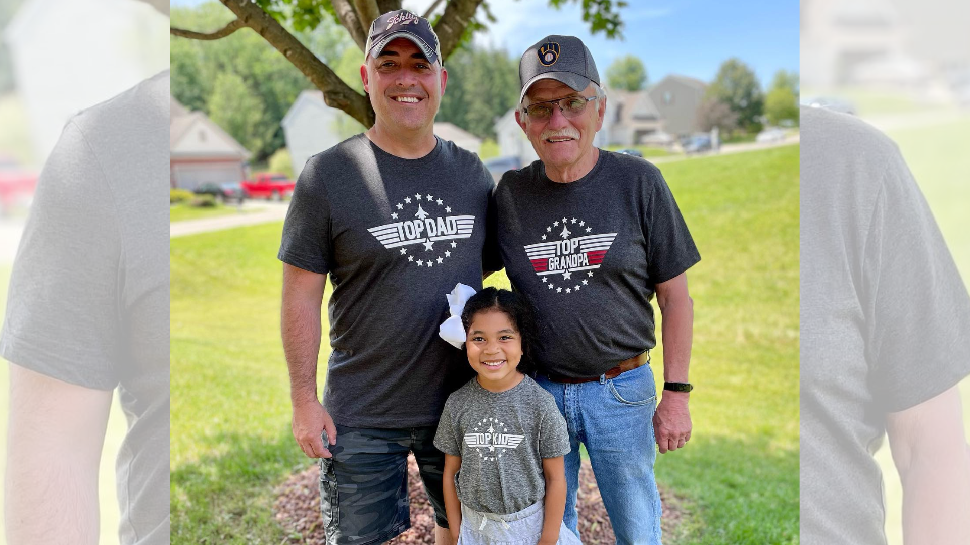 Two men and a little girl are standing next to each other in a field.