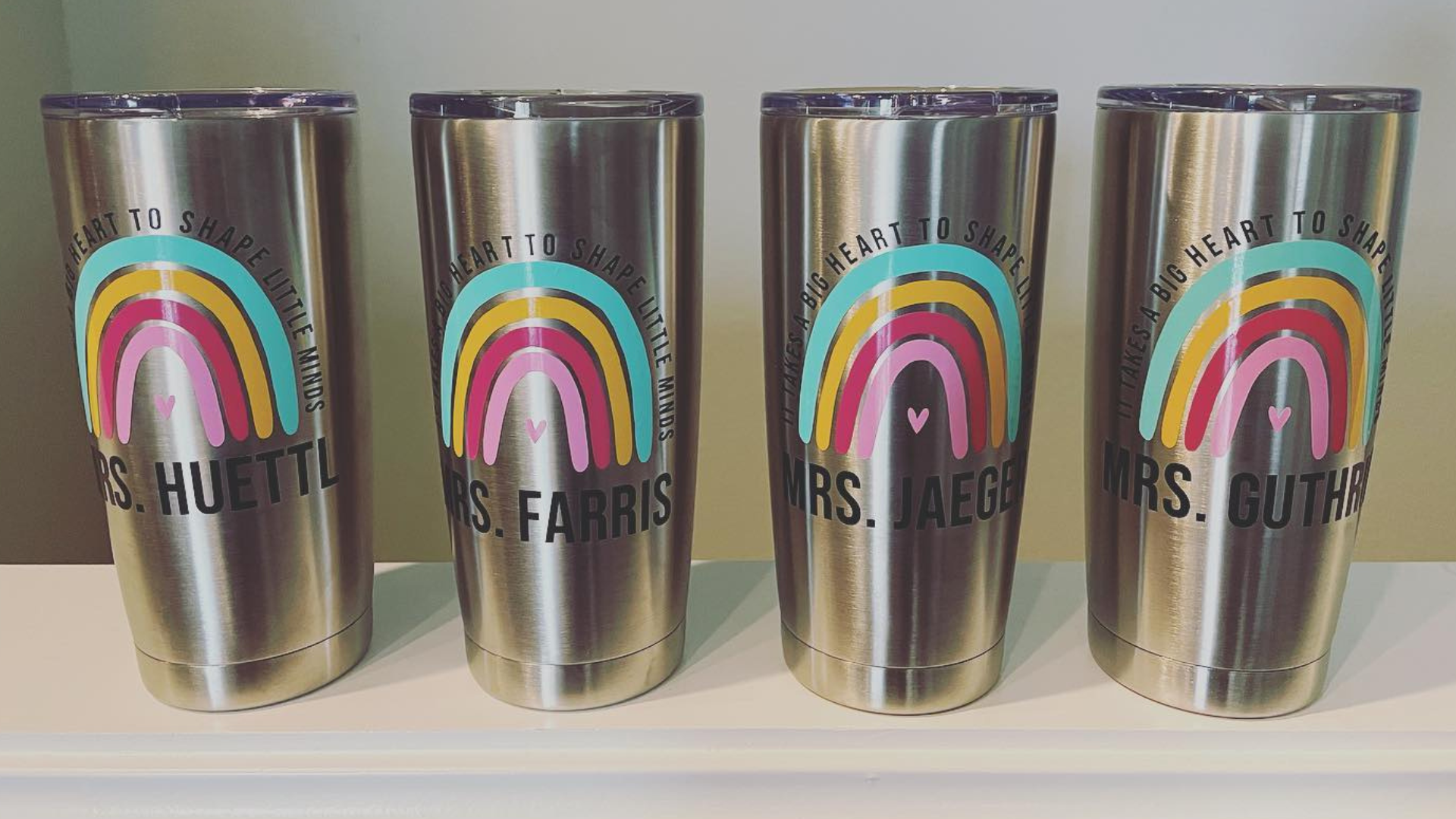 Four stainless steel tumblers with rainbows on them are sitting on a table.