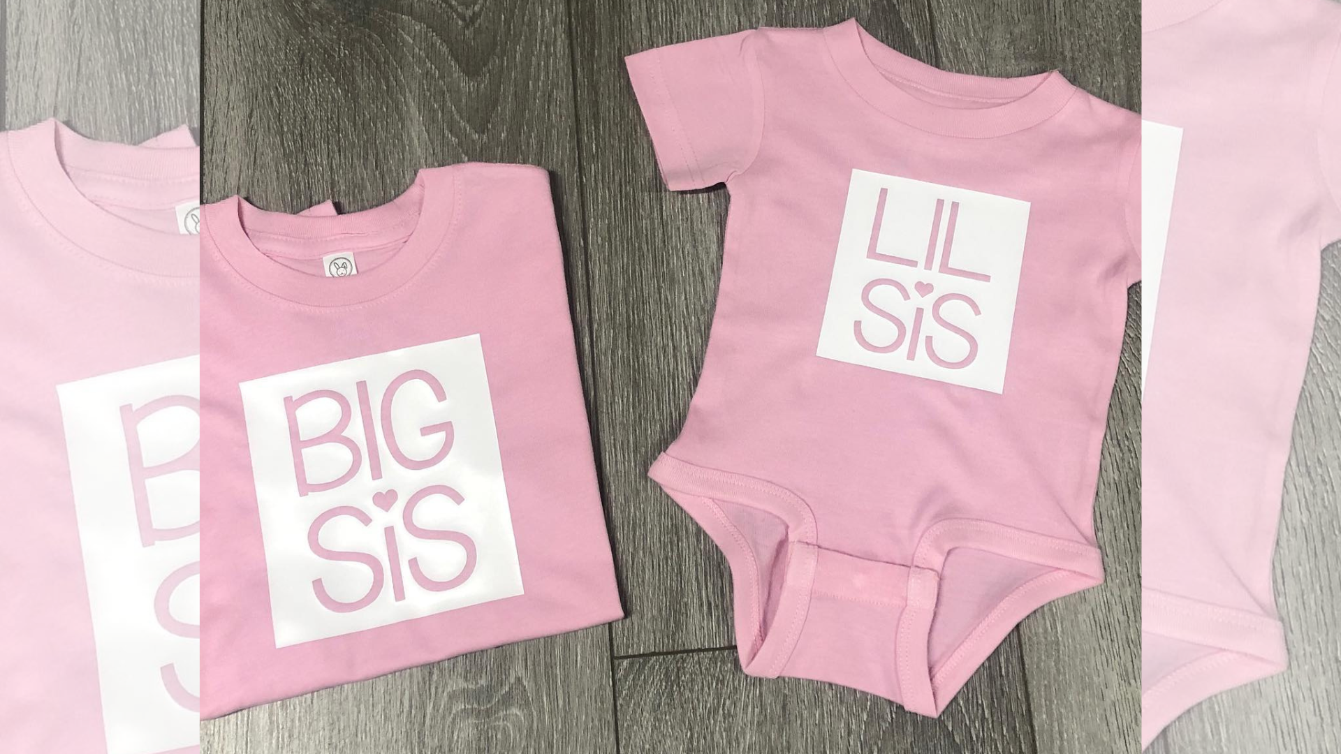 Two pink shirts and a pink onesie are sitting on a wooden table.